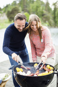Happy couple barbecuing on pier