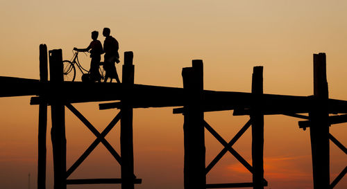 Silhouette of people on pier at sunset