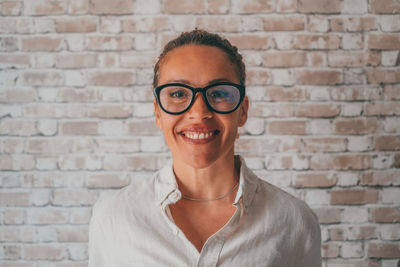 Young woman wearing sunglasses against wall