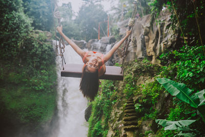 Young woman on swing against waterfall