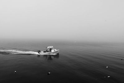 Man sailing in boat on sea against sky