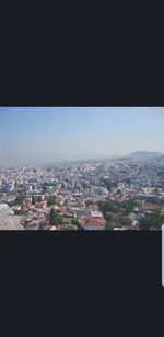 Aerial view of buildings in city against clear sky