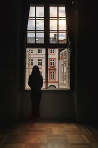 Rear view of silhouette man standing against window