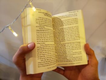 Cropped image of hand holding book with text