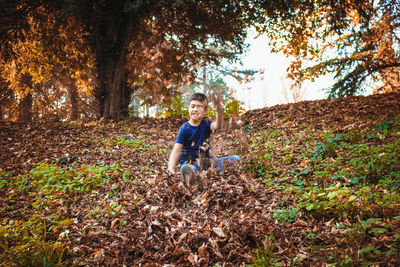 Boy playing with dry leaves in park