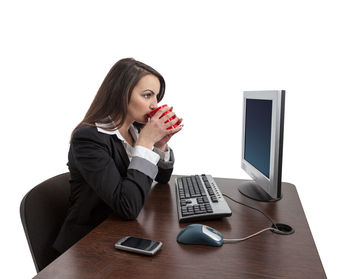 Young woman using mobile phone while sitting on table