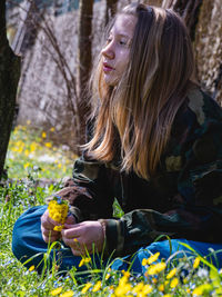 Portrait of smiling young woman sitting on tree