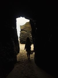 Rear view of woman standing in cave