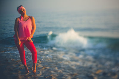 Young woman standing at beach against sky