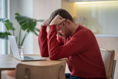 Unemployed desperate sitting at table in depression because of money loss, bankruptcy, job failure