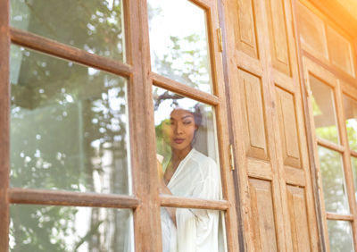 Low angle view of woman looking through window