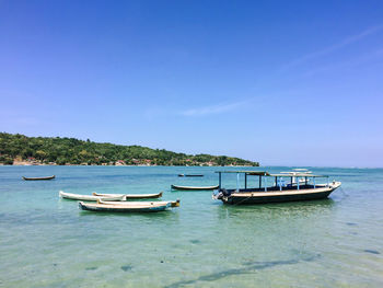 Boats anchored on sea against clear sky