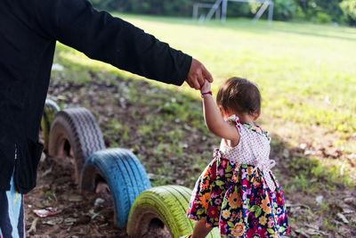 Children balancing joyfully on the wheels of a car tire.