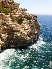 Rock formation in sea against clear sky