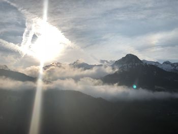 Sunlight streaming through clouds over mountains
