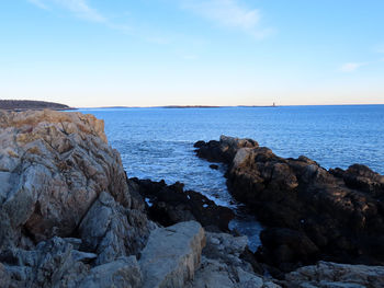 Rocks on sea shore against sky