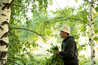 Side view of young man standing against plants