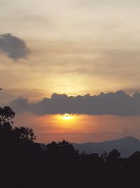 Scenic view of silhouette mountains against orange sky