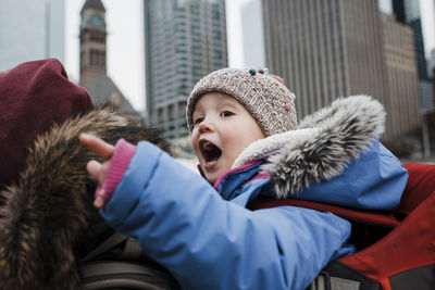 Side view of father piggybacking daughter while walking on city street