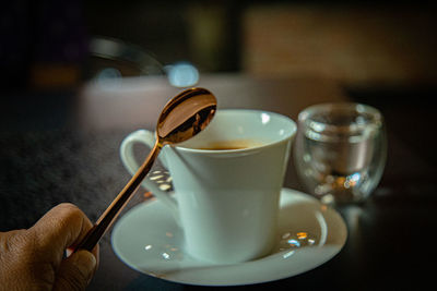 Cropped hand holding coffee on table