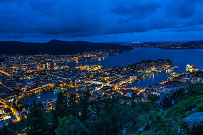 High angle view of illuminated city by sea against sky