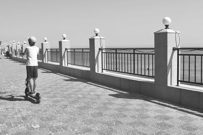 Rear view of people standing on railing against clear sky