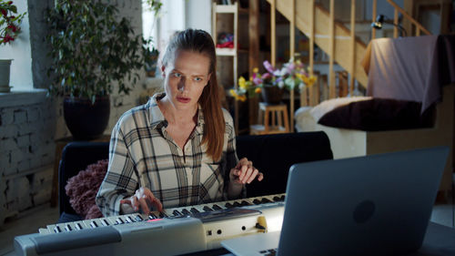 Woman learning piano from laptop