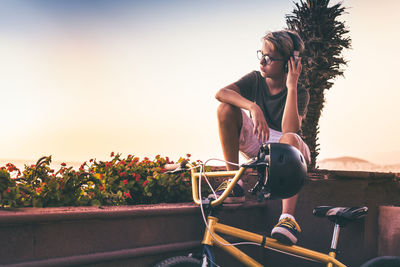 Woman on bicycle against clear sky during sunset