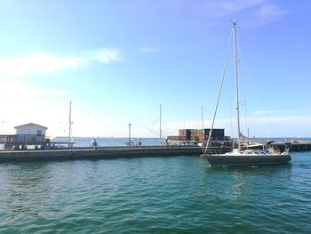 Sailboats moored at harbor against sky
