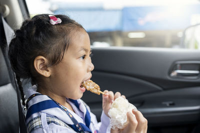 Close-up of boy eating food in car