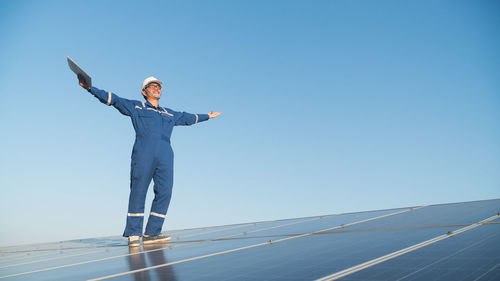 Full length of man standing against blue sky