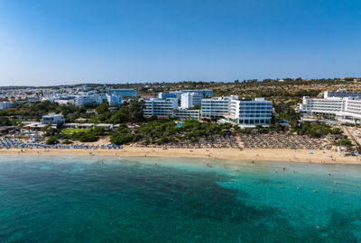 Buildings by sea against clear sky