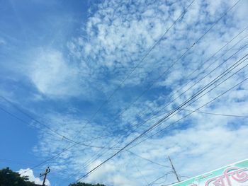 Low angle view of electricity pylon against cloudy sky