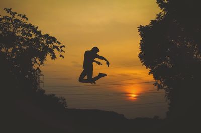 Silhouette of man jumping against sky during sunset