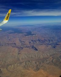 Aerial view of airplane flying over landscape against sky