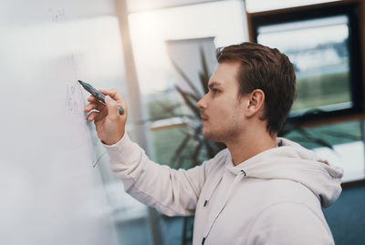 Young business man writes on a whiteboard, he is busy and works hard in his start up company