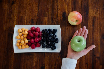 High angle view of hand holding apples on table