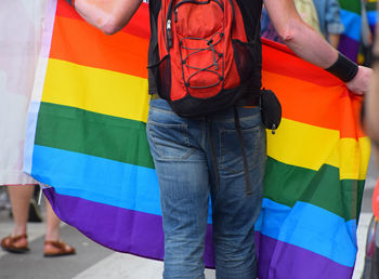 Midsection of man standing with rainbow flag