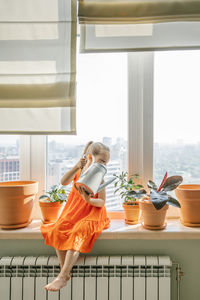 Woman standing by potted plant on table