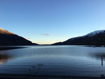 Scenic view of lake and mountains against clear blue sky