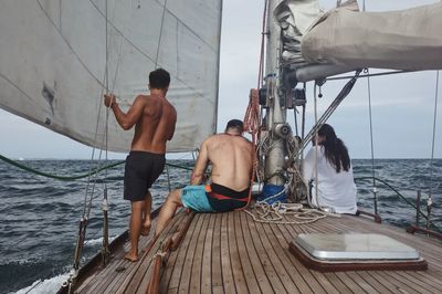 People on boat sailing in sea against sky