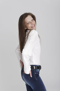 Portrait of young woman standing against white background
