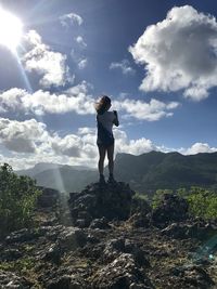 Rear view of man standing on mountain against sky