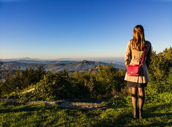 Rear view of woman standing on grassy field