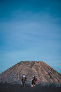 People riding motorcycle on mountain against sky