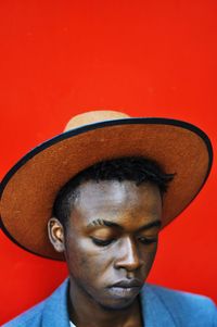 Close-up of man wearing hat against red wall