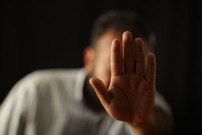 Man showing stop gesture against black background