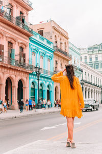 Rear view of woman standing on street against buildings