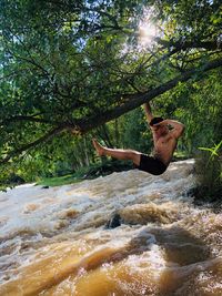 Young man on tree in water