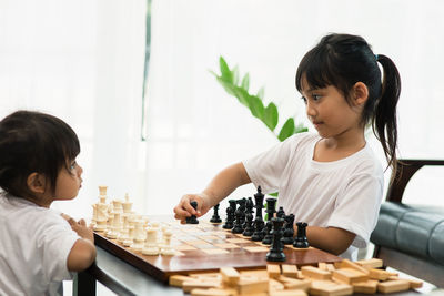 Cute sisters playing chess at home